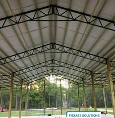 the inside of a large metal structure that is covered with white fabric and wood beams