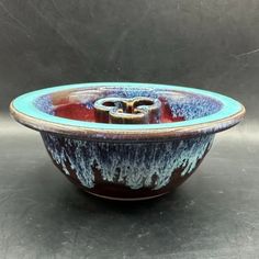 a blue and red bowl sitting on top of a black countertop next to a gray wall