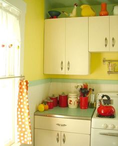 a kitchen with white cabinets and green counter tops next to a stove top oven in front of a window