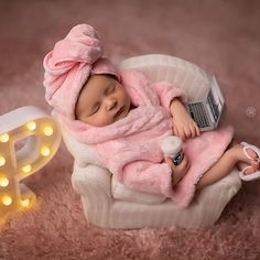 a baby doll is sleeping on a chair next to a light up letter and a laptop