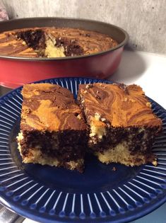 a blue plate topped with two pieces of cake next to a pan filled with cakes