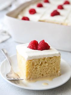 a piece of cake with white frosting and raspberries on top is sitting on a plate