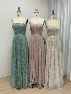 three dresses on mannequins in front of a window