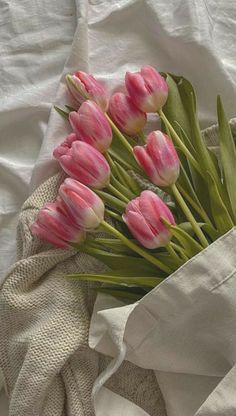 a bouquet of pink tulips sitting on top of a white cloth