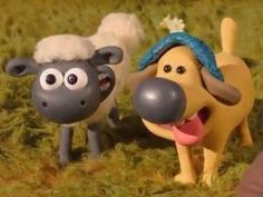 two toy sheep standing next to each other on a grass covered field, one with its tongue out