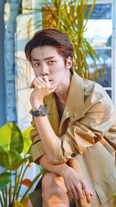 a young man sitting on top of a wooden bench next to a potted plant