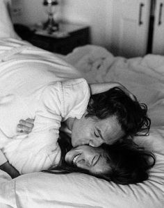 black and white photograph of two people laying on a bed, one is hugging the other