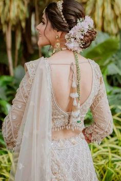 the back of a woman's wedding dress with flowers in her hair and jewelry