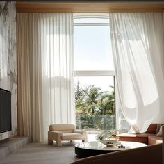 a living room filled with furniture and a flat screen tv mounted on a wall next to a window