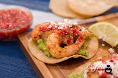 shrimp and guacamole on tortilla shells with salsa in the background