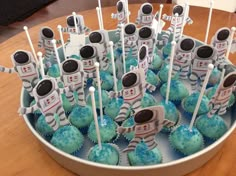 cupcakes with blue frosting and robot decorations in a bowl on a table