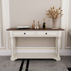 a white table with two drawers and some vases on top of it in front of a beige wall