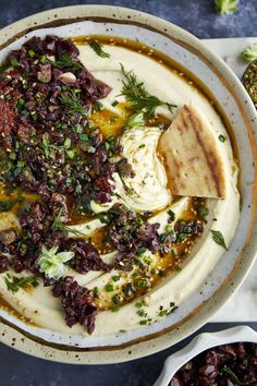 a bowl filled with hummus, olives and pita bread