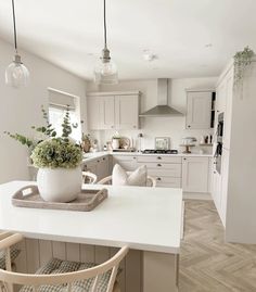 a kitchen with white cabinets and an island in the middle, surrounded by two chairs