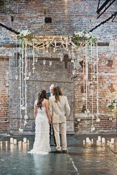 a bride and groom standing in front of a brick wall