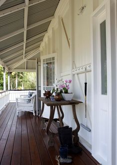 the porch is covered with white paint and wood flooring, along with a small table that has flowers on it