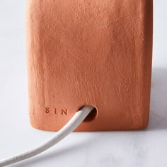 a close up of a cord connected to an orange piece of clay with the word sin on it