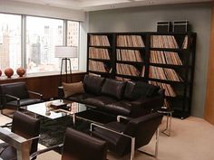 a living room filled with lots of furniture and tall windows covered in bookshelves