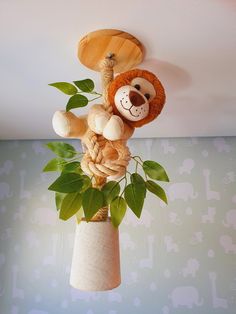 a stuffed animal hanging from the ceiling in a room with blue wallpaper and green leaves