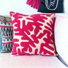 a pink and white pillow sitting on top of a couch next to a black purse