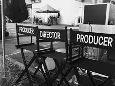 two black chairs sitting next to each other in front of a building with the word director written on them