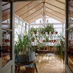 the inside of a greenhouse with potted plants and tables in it's center