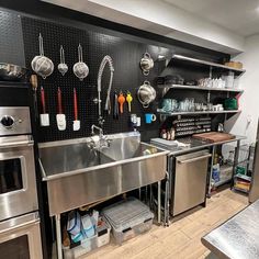 an industrial kitchen with stainless steel appliances and utensils hanging on the wall above the sink