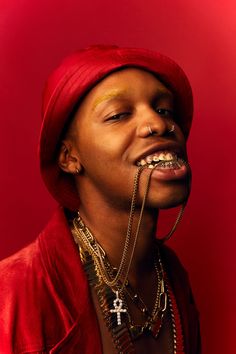 a man with his mouth covered in chains and wearing a red hat, standing against a red background