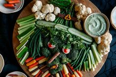 a platter with vegetables and dips on it