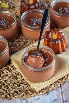 chocolate pudding in small glass jars with spoons on a woven place mat next to bananas