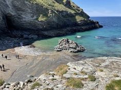 people are standing on the rocks by the water and looking out at the ocean from above