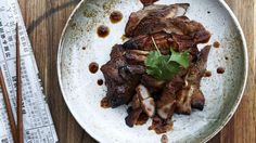 a white plate topped with meat and veggies on top of a wooden table