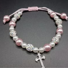 a pink and white beaded bracelet with a silver cross charm on it's end