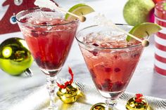 two glasses filled with red liquid and garnished with limes