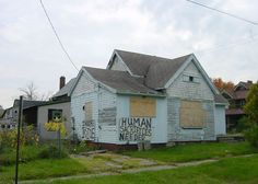 an old house with boarded up windows and graffiti on the sidings that reads human services needed