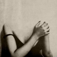 a black and white photo of a woman with her hands on her face, leaning against a wall