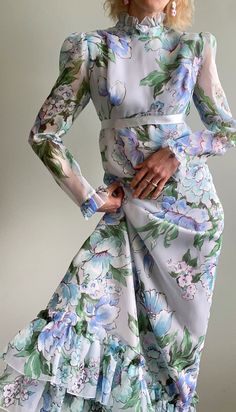 "Incredible vintage 1960s ethereal floral maxi dress with sheer sleeves, empire waist with long blue satin ribbon that forms a bow at the back, high ruffled Victorian collar neckline, tiered ruffled hemline and zipper closure at the back. The floral fabric is just stunning in a baby blue, pink, purple, green and white colour palette. The dress is fully lined (except for sleeves). Would fit a size x-small to small but please see measurements below.  Maker/Designer: Irving Nadler - Montreal Condition: Very good vintage condition  Measurements (taken with garment lying flat, unstretched - double for bust/waist/hip):               shoulders seam to seam: 15\"               bust: 17\"                 empire waist: 14\"               hip: 19\"               length (shoulder to bottom hem): 53.5\ 1970s Style Silk Dresses For Spring, Dress With Sheer Sleeves, Victorian Collar, Floral Dress Outfits, Purple Floral Dress, Blue Pink Purple, Purple Outfits, White Colour, Blue Satin