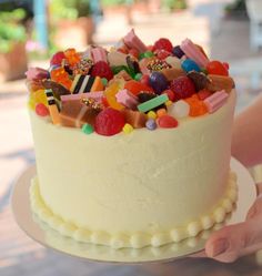 a person holding a cake with lots of candy on it