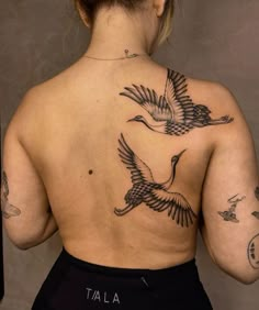 the back of a woman's body with tattoos on her upper and lower back