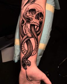 a hand with a skull and snake tattoo on it's left arm, which is holding