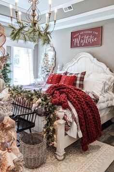 a bedroom decorated for christmas with red and white decorations on the bed, chandelier and wreaths