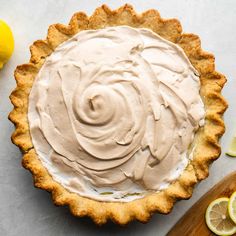 a pie with frosting on top next to sliced lemons