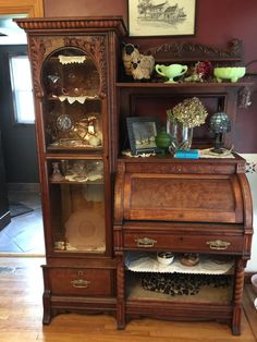 an old wooden china cabinet with glass doors and shelves on top of it in a living room