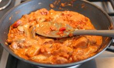 a pan filled with food sitting on top of a stove next to a wooden spoon