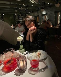 a woman sitting at a table with drinks