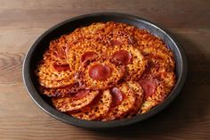 pepperoni pizza in a black bowl on a wooden table with wood grained surface