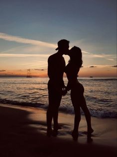 a couple kissing on the beach at sunset