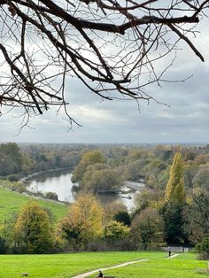 two people are sitting on a bench overlooking a river