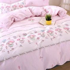 a bed with pink and white comforters, pillows and a potted plant on it