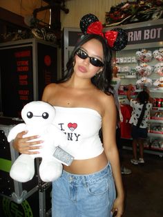 a woman holding a white teddy bear wearing minnie mouse ears on her head and sunglasses